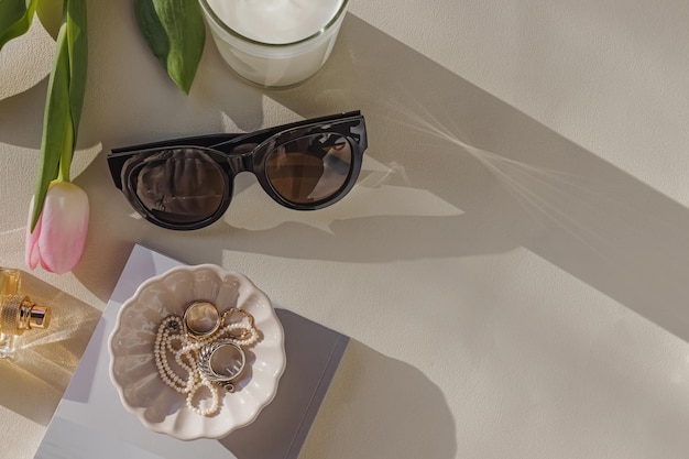 Acosta con joyas en un pequeño plato de tulipán y gafas de sol en la luz natural