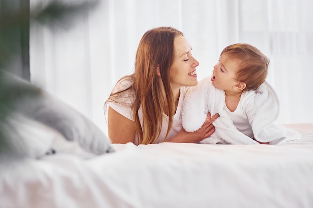 Acostada en la cama Madre con su pequeña hija está en casa juntos