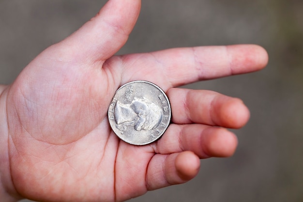 Acostado en la mano de la moneda americana del niño en un cuarto. Primer plano de la foto con una pequeña profundidad de campo.