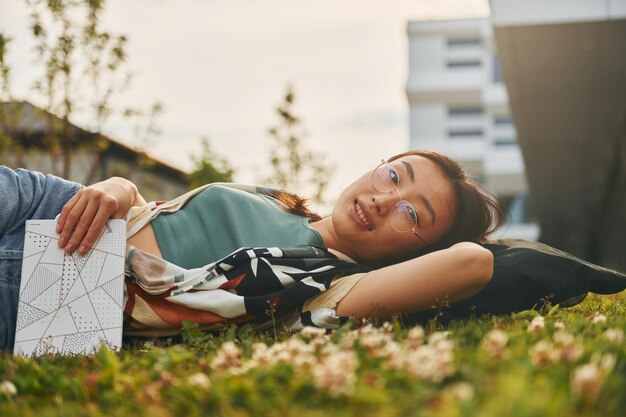 Acostado en el pasto Joven mujer asiática está al aire libre durante el día