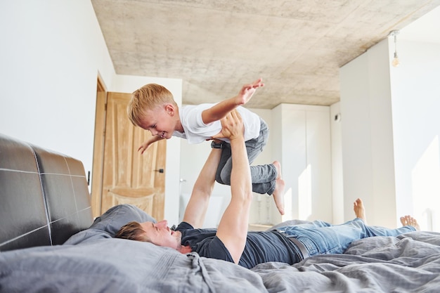 Acostados en la cama Padre e hijo están juntos en casa