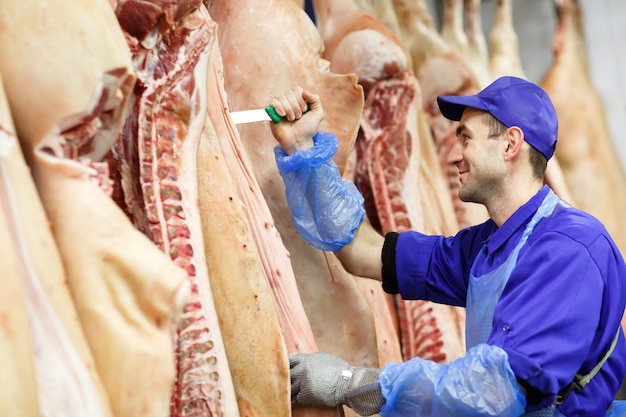 Foto açougueiro cortar carne de porco na fabricação de carne.