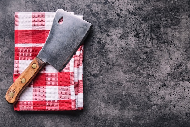 Açougueiro. Cutelos de carne de açougueiro vintage com toalha de pano no concreto escuro ou placa de cozinha de madeira.