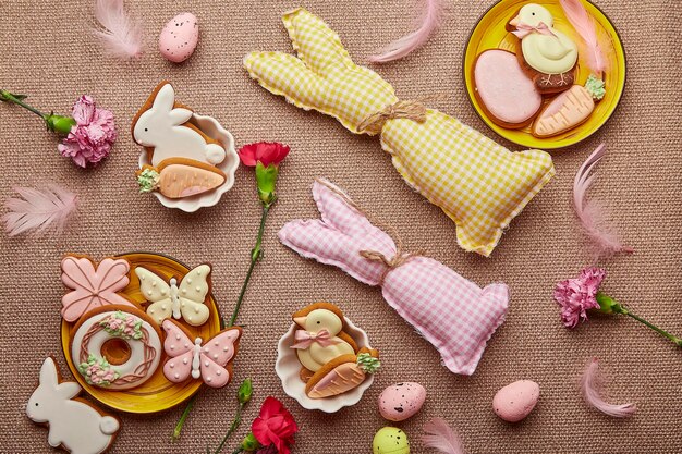 Acristalamiento tradicional Galletas de Pascua juguetes de conejito hechos a mano flores rosadas Fondo estético de Pascua de primavera endecha plana