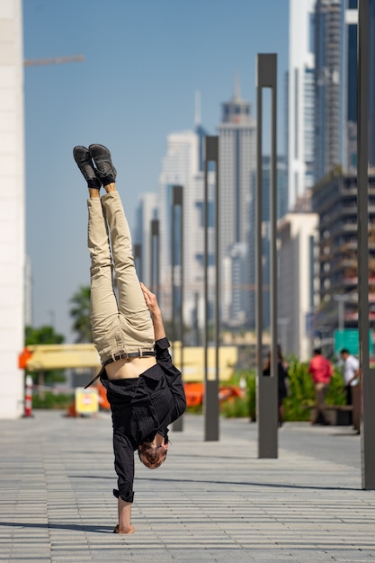 Acrobat mantém o equilíbrio entre as mãos com a paisagem urbana borrada de dubai