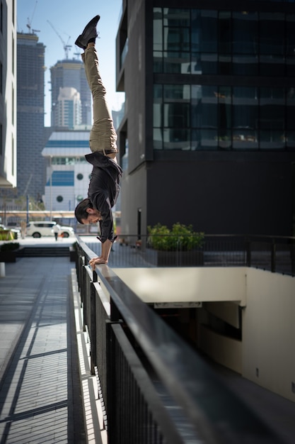 Acrobat mantiene el equilibrio una de las manos con el paisaje urbano borroso de Dubai