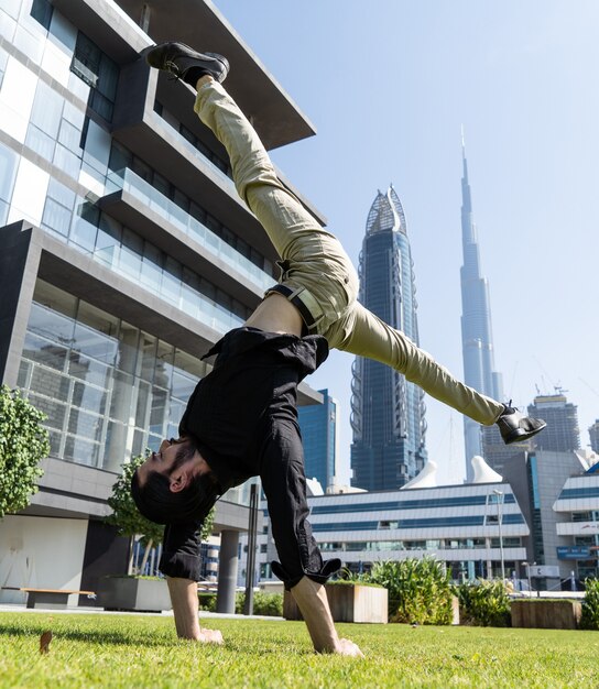 Acrobat mantiene el equilibrio una de las manos con el paisaje urbano borroso de Dubai