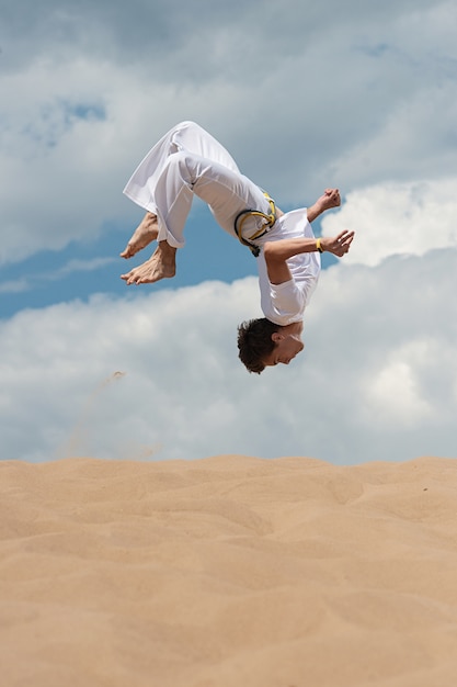 Acrobat realiza um truque acrobático, dar cambalhotas na praia