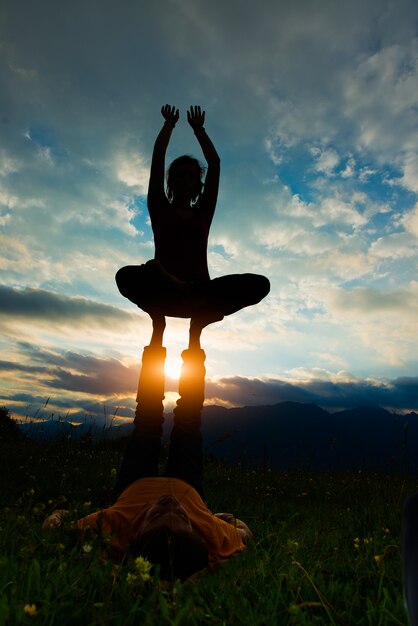 Acroyoga mujer de sexo masculino en un ambiente romántico en la naturaleza en las montañas al atardecer