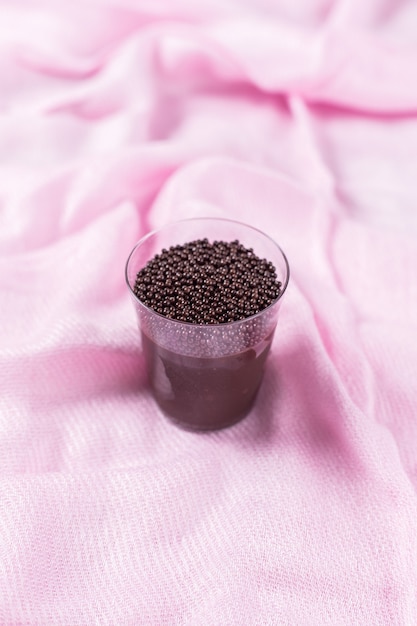 Acrylbecher mit Brigadeiro und Schokoladenstreuseln auf rosa Hintergrund