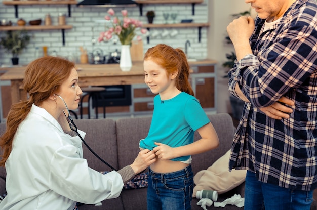 Actitud optimista. Niña enferma positiva de buen humor mientras se realiza un examen médico