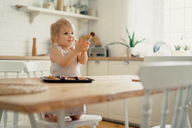 Una actividad interesante para el bebé Un niño juega en la cocina con moldes para pasteles