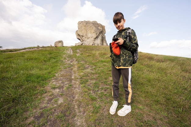 Actividad en el soleado día de otoño niño explorando la naturaleza Niño usar mochila senderismo y hacer fotos en el teléfono