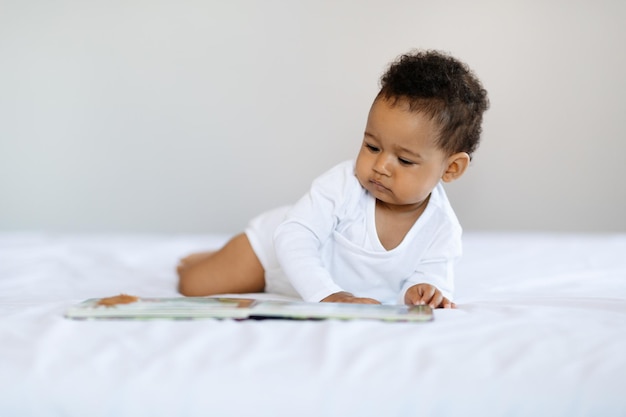 Actividades de desarrollo del bebé Cute Little Black Boy relajante en la cama con libro