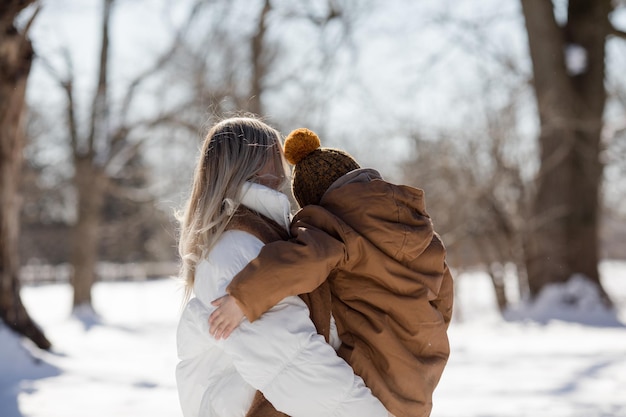 Actividades familiares al aire libre para felices vacaciones de invierno Madre feliz y dos hijos jugando a las bolas de nieve en la calle nevada en el suburbio Familia feliz en el fin de semana de invierno Vacaciones de Navidad