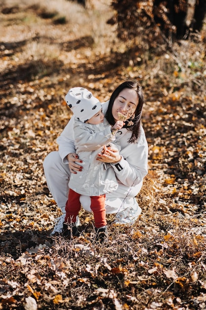 Actividades familiares de otoño madre de familia feliz y niña pequeña jugando al aire libre en el parque de otoño