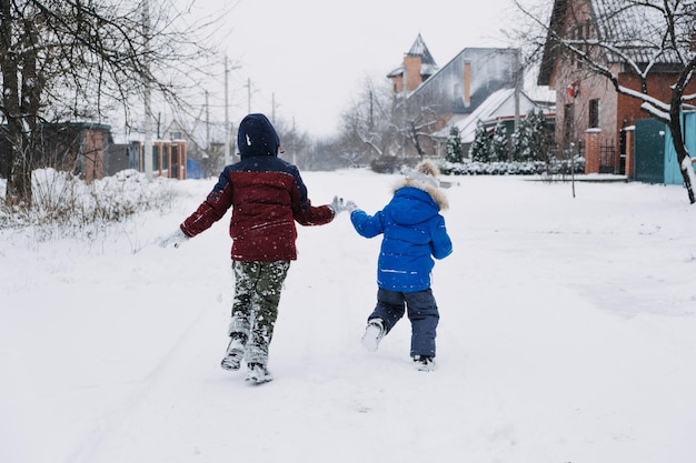 Actividades de invierno al aire libre para niños niños jugando en los suburbios patio trasero de invierno reuniendo niños teniendo