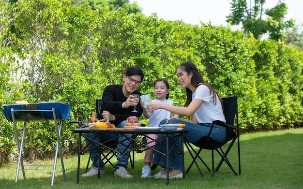 Las actividades de vacaciones familiares incluyen padre, madre e hijos con barbacoa para acampar y jugar juntos en el patio felizmente de vacaciones