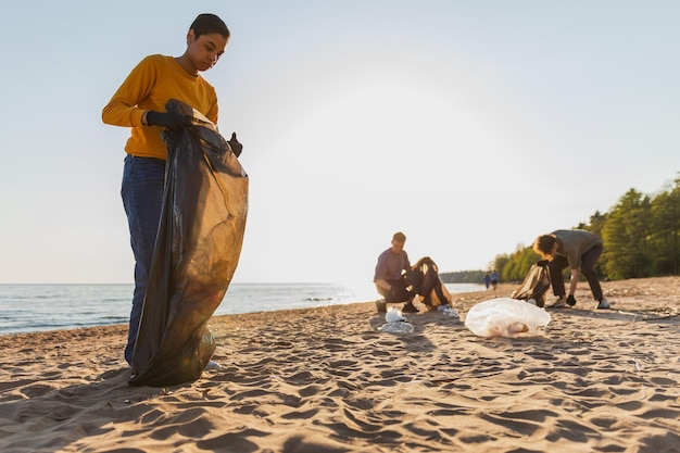 Activistas voluntarios del día de la tierra recogen basura limpiando la playa zona costera mujer y hombre pone