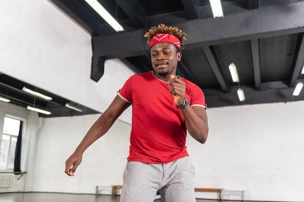 Activo y guapo bailarín joven que tiene una repetición rutinaria de su actuación mientras tiene accesorios rojos