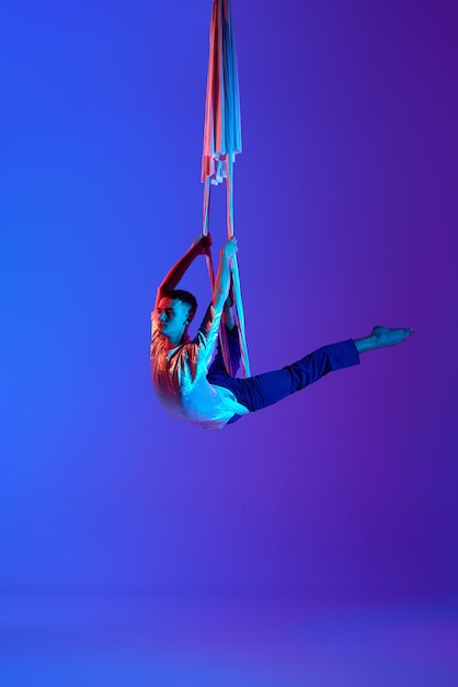 Foto actuación artística joven acróbata entrenando con cintas aéreas haciendo trucos de gimnasia contra