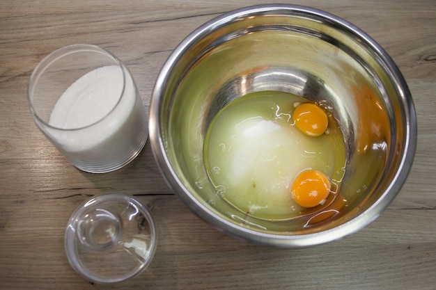 Açúcar branco e dois ovos em uma tigela metálica