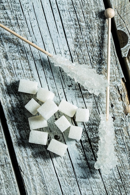 Açúcar cristalizado em palito de madeira e cubos de açúcar na mesa de madeira Vista superior