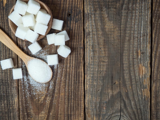 Açúcar granulado em uma colher de pau closeup em uma velha mesa de madeira