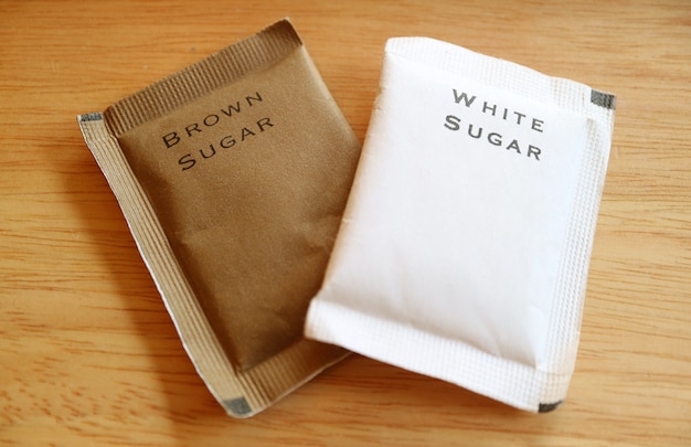 Açúcar mascavo e açúcar branco em sacos de papel