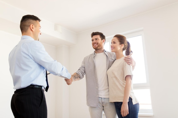 Foto acuerdo de hipoteca, la gente y el concepto de bienes raíces - pareja feliz y agente de bienes raíces con tablet pc computadora estrechando la mano en la nueva casa