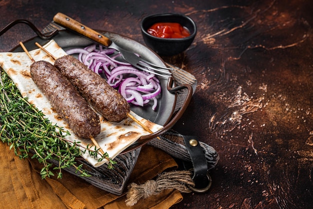 Adana kebab turca de carne picada de cordero en brocheta con pan plano y cebolla Fondo oscuro Vista superior Espacio de copia