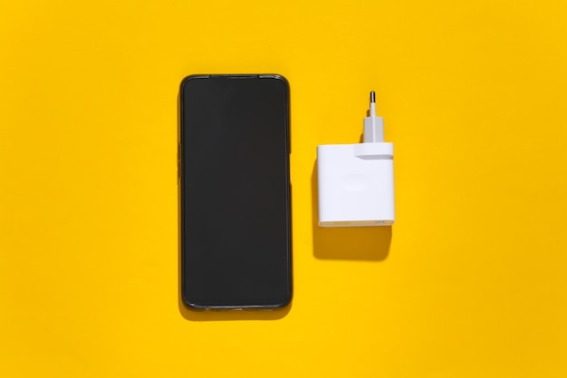 Adaptador de smartphone e carregador em fundo amarelo brilhante com sombra profunda.