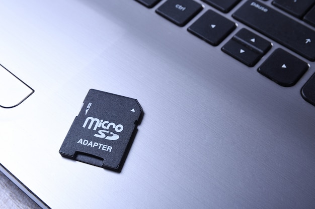 Adaptador de tarjeta de memoria Micro SD en el teclado gris portátil sobre la mesa de madera. de cerca