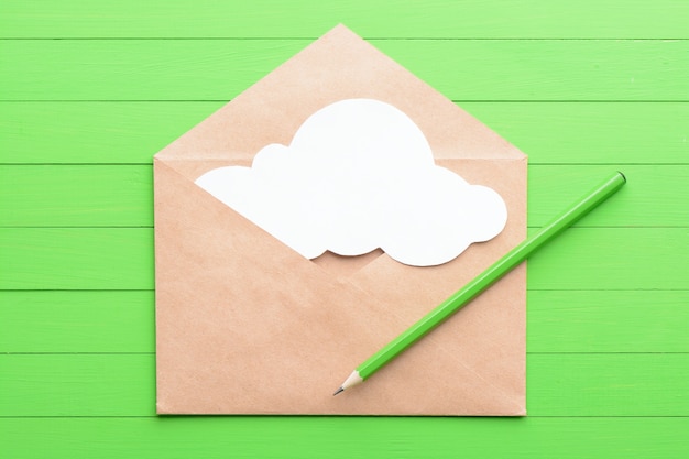 Adesivo branco em forma de nuvens no envelope sobre fundo verde de madeira