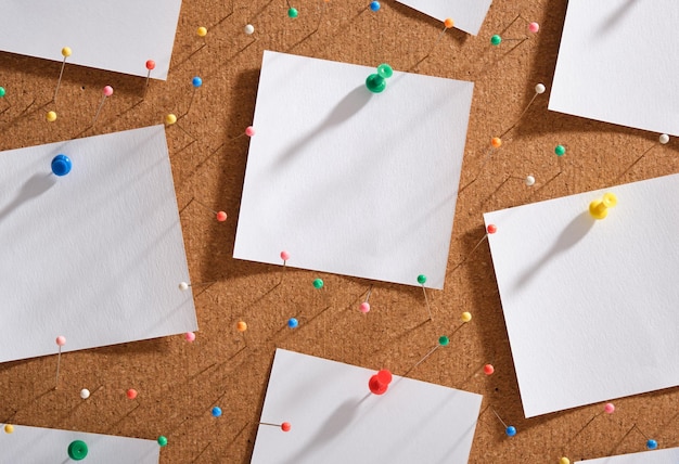 Adesivos de papel branco fixados na placa de parede de cortiça, tachas de pinos multicoloridos conceito de espaço de trabalho do loft