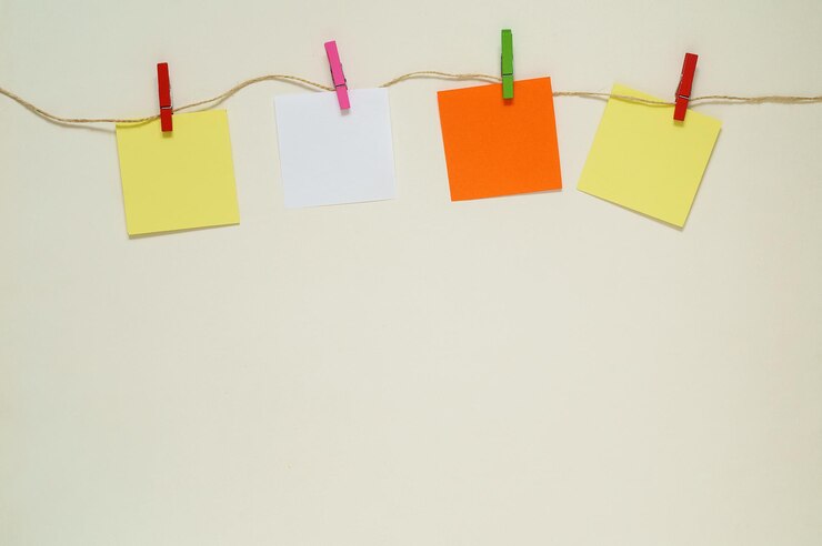 Foto adesivos de papel laranja, amarelo e branco com prendedores de roupa em uma corda. copie o espaço