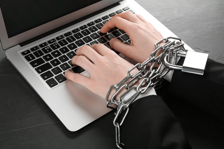Foto adicción a internet hombre escribiendo en la computadora portátil con las manos encadenadas en el primer plano de la mesa negra