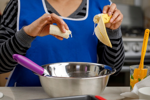 Adicionando banana a um recipiente para fazer uma panqueca de banana conceito de cozimento doméstico