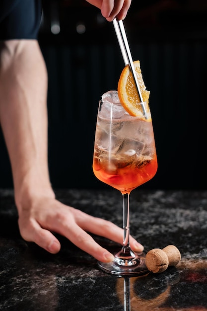 Adicionando laranja em aperol spritz preparando coquetel em um bar