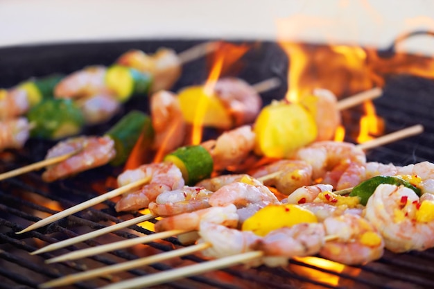 Adicionando um ótimo sabor defumado closeup de espetos de camarão cozinhando na grelha