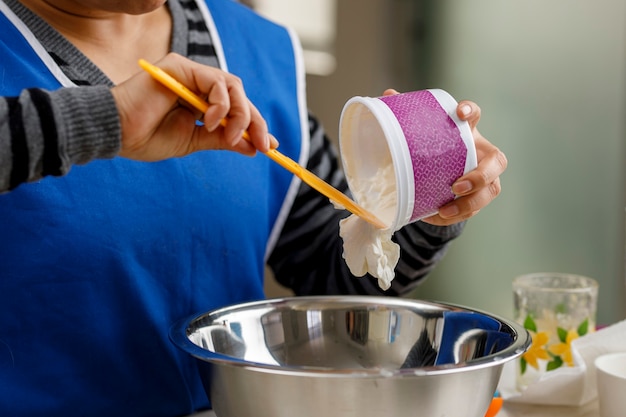 Adicionar creme de leite em um recipiente para preparar uma sobremesa conceito de panificação caseira