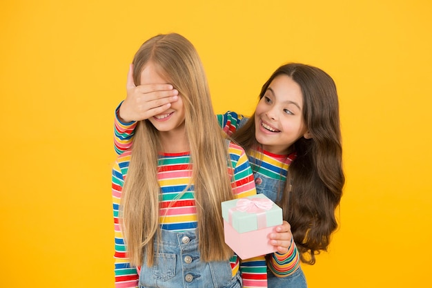 Adivinha quem. Menina recebendo presente surpresa. Surpresa de aniversário. Criança pequena bonita fazer surpresa para um amigo ou irmã. Que surpresa agradável. Celebração do feriado.