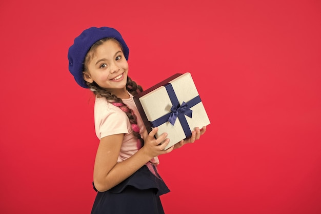 Adivinhe com o que seu filho sonha Melhores brinquedos e presentes de natal Garotinha de chapéu de boina segura caixa de presente Criança animada por desembalar o presente Pequena garota fofa recebeu pacote de presente com laço de fita