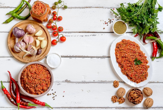 Adjika und Zutaten georgische Küche Frisches Gemüse Gewürze Nüsse Kräuter auf weißem Hintergrund mit Kopierraum Draufsicht Schöner Lebensmittelhintergrund