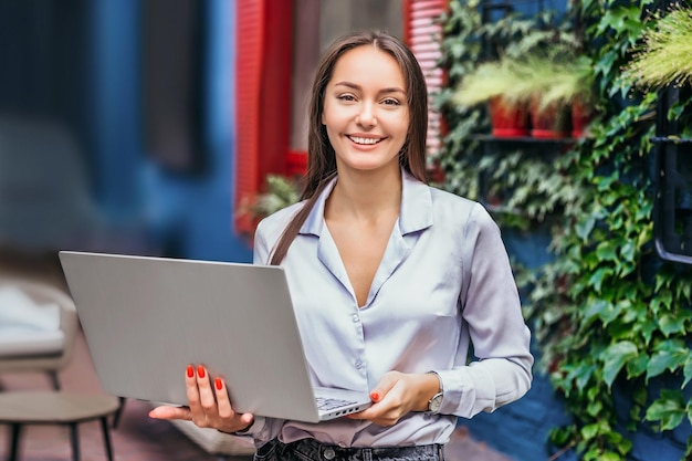 Administrador de restaurante de mujer morena caucásica de pie y trabajando en la computadora portátil