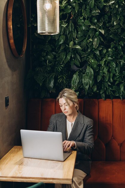 Administrador de restaurante de mujer de negocios maduros sentado y trabajando en la computadora portátil