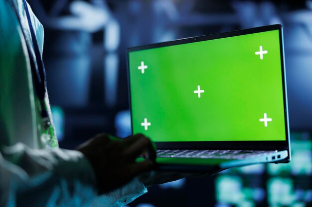 Administrador de sistemas del centro Dara ejecutando código y programación en computadora portátil de clave cromada solucionando problemas y actualizando el espacio de trabajo de alta tecnología diseñado para acomodar filas de servidores completamente operativos