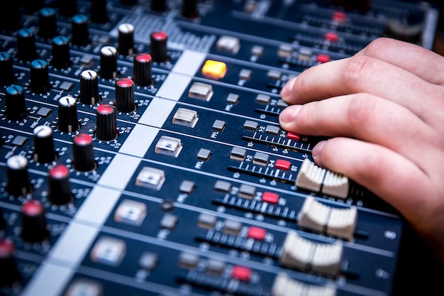 El administrador de sonido está trabajando en el mezclador de audio, preparando una nueva mezcla de una canción o trabajando en un evento en vivo