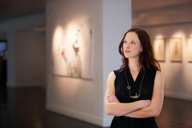 Admirando un siglo de arte Foto de una mujer joven mirando pinturas en una galería