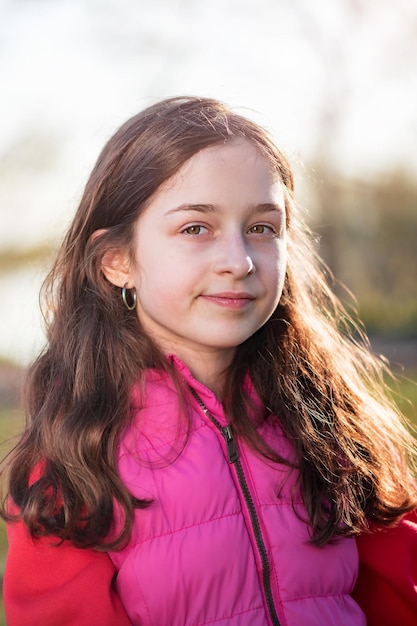 Adolescencia. Niña en la naturaleza con un chaleco rosa. Una niña de 11 años está de muy buen humor.